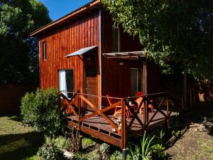 a red cabin with a wooden porch and a gate at Casa Joha - Casa en Chapa a 1 cuadra de Luna Roja para 4 PAX - Hola Sur in Chapadmalal