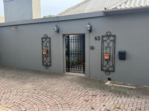 a white building with a gate with two potted plants at CityScape Nest Suite Unit 2 in Mossel Bay