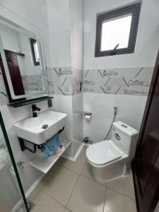 a white bathroom with a toilet and a sink at Two-bedroom flat - River view, elevator, free inside car parking in Mỹ Phước