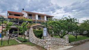 a stone wall in front of a house with a building at Guest House Gordana in Banjol