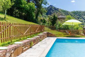 a swimming pool with an umbrella and a fence at El Refugio I de Verdiago in Verdiago