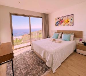 ポンタ・ド・ソルにあるHoliday House Caetanoの大きなベッドと大きな窓のある寝室