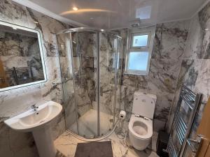 Un baño con ducha, inodoro y lavabo. en Britlodge Living, en Mánchester