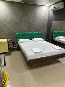 een slaapkamer met een groot bed met een groen hoofdeinde bij Rodotel Vênus Prime in Acreúna