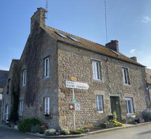 a stone building with a street sign in front of it at Rêve du Revert in Roz-sur-Couesnon