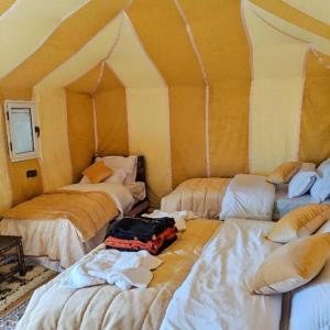 a room with three beds with a suitcase on the floor at Acacia Luxury Camp in Merzouga