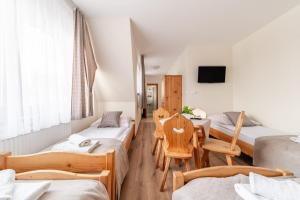a room with four beds and a table and chairs at Willa Leśny Potok in Poronin