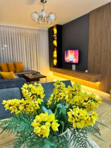 a vase of yellow flowers on a table in a living room at AR Apartment in Kosovo Polje