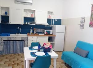 a blue kitchen with a table and a blue couch at Mare Sole Vento 38 Punta Prosciutto in Torre Colimena