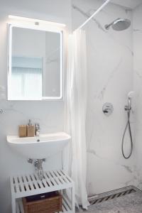 ein weißes Badezimmer mit Waschbecken und Spiegel in der Unterkunft Hanslgasse Private Rooms in Wien