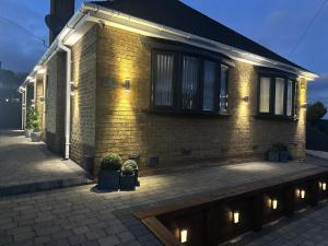 a brick house with lights on the side of it at Modern Retreat with Hot Tub and Cinema in Cuckney