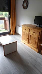 a living room with a television and a wooden cabinet at Studio 4pers vue piste in Le Corbier