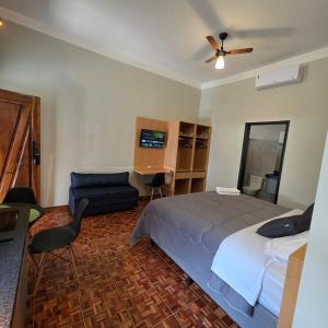 a bedroom with a bed and a couch and a fan at Zuccaro Studio 4 in Bauru