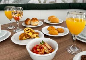 ein Tisch mit Tellern voller Essen und Gläsern mit Orangensaft in der Unterkunft Santé Vivre L'Experience by Livá OFICIAL in Búzios + 26 Fotos