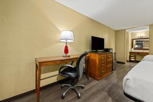 a hotel room with a desk with a bed and a lamp at Americas Best Value Inn - Wilson in Wilson