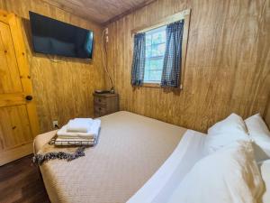 une chambre avec un lit et une télévision au mur dans l'établissement Tiny Log Cabin near Fossil Rim | Countryside Views, à Glen Rose