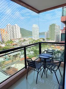 a balcony with three chairs and a table and a view at Lar e Mar PG in Praia Grande