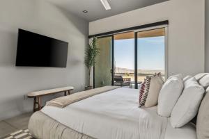 a bedroom with a large bed with a flat screen tv at Sunstill by Fieldtrip Modern w Custom Pool Spa Views in Joshua Tree