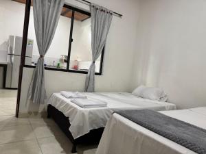 a bedroom with two beds and a window with curtains at Casa descanso en tocaima in Tocaima