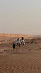 a group of people riding horses in the desert at FYAFY Bidiyah Bedouin Camp in Bidiyah