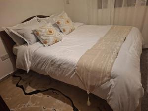 ein Bett mit weißen Laken und Kissen in der Unterkunft Ben's Apartment in Ngong