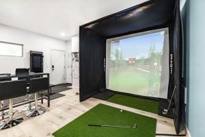 a room with a golf simulator with a putting green at The Q - Austin Family Home - Hot Tub & Golf Sim in Austin