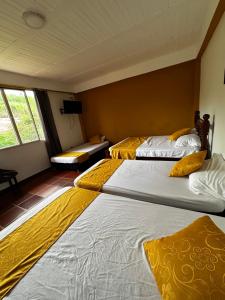 two beds in a room with yellow blankets on them at Finca los Bohíos in Santa Rosa de Cabal