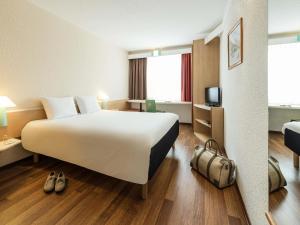 a hotel room with a large bed and a tv at ibis Hotel München Garching in Garching bei München +40 photos