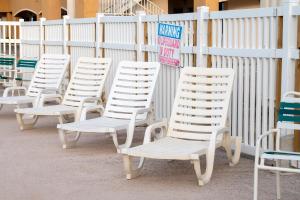 a row of white chairs sitting next to a fence at Island Inn By OYO Galveston Beach, TX in Galveston