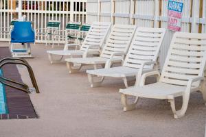 a row of white chairs sitting next to a pool at Island Inn By OYO Galveston Beach, TX in Galveston