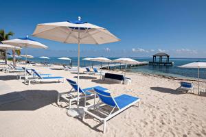 grupa leżaków i parasoli na plaży w obiekcie Rum Point Resort 404 w mieście Driftwood Village