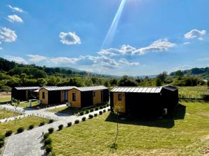 a row of huts in a field with a rainbow in the sky at Kapija Svrljiga in Svrljig