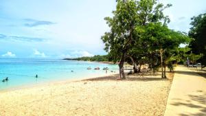 a beach with people in the water and trees at villa Rony in Port-Louis