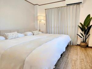 uma grande cama branca num quarto com uma planta em Luna Luxury 4BR Family Villa with Parking - 2 mins from Osaka-ko Station, near EXPO, USJ, Kaiyukan em Osaka