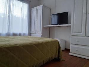 Un dormitorio con una cama con un televisor de pantalla plana. en Tu casita en sierras, en Sierra de los Padres