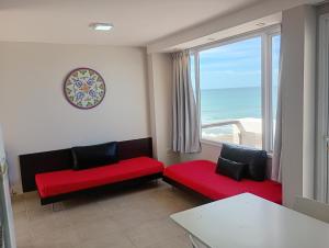 een woonkamer met rode en zwarte stoelen en een raam bij Bahia creek in Las Grutas