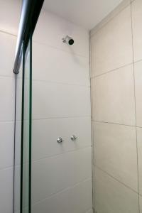 a shower with white walls and chrome fixtures at Xavi Studio - Superior in Bauru