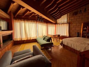 een slaapkamer met een bed en een bank en stoelen bij Rustic house with stunning lake view in Valle de Bravo