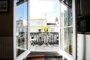 uma janela aberta com uma mesa com flores amarelas numa varanda em Sillwood Balcony Apartment - Central - by Brighton Holiday Lets em Brighton & Hove