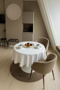 a white table with two cups and cookies on it at Manor Suite Amsterdam in Amsterdam
