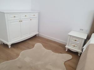 ein Schlafzimmer mit einer weißen Kommode, einem Bett und einem Tisch in der Unterkunft White Silk - Premium Apartment with free underground parking in Iaşi + 16 Fotos