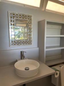 a bathroom with a white sink and a window at Charming bungalow with sea view facing Marina Taina in Punaauia +20 photos