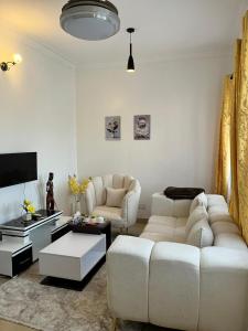 By the Coastals في مومباسا: غرفة معيشة مع كنبتين بيضاء وتلفزيون