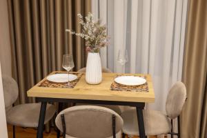 a wooden table with a vase of flowers and glasses at Lux Holidays 221 in Durrës