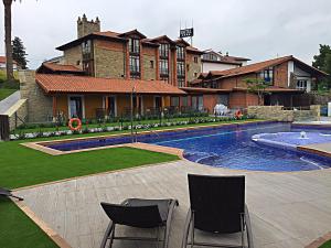 a house with a swimming pool in front of a house at Hotel Marfrei in Hinojedo
