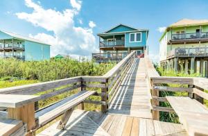 a boardwalk leading to the beach with houses at Blue Waves - Beachside Calm, Gulf Views for Miles in Freeport