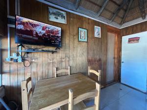 ein Esszimmer mit einem Holztisch und einem Flachbild-TV in der Unterkunft El rinconcito del amor pdd in Punta Del Diablo