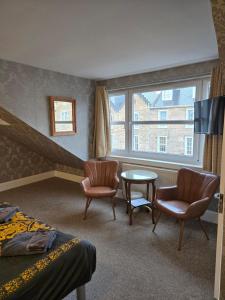 a hotel room with two chairs and a table and a window at IVY- Braveheart Guest House in Edinburgh