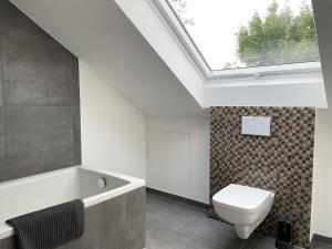 a bathroom with a toilet and a bath tub with a skylight at 2 bedroom apartment with 4 beds in Pfaffenhofen PAF01 in Pfaffenhofen +5 photos