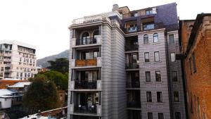 a tall gray building with balconies in a city at Vere Side Rooms in Tbilisi City